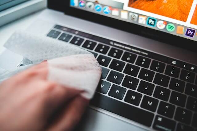 Person Cleaning Laptop Keyboard